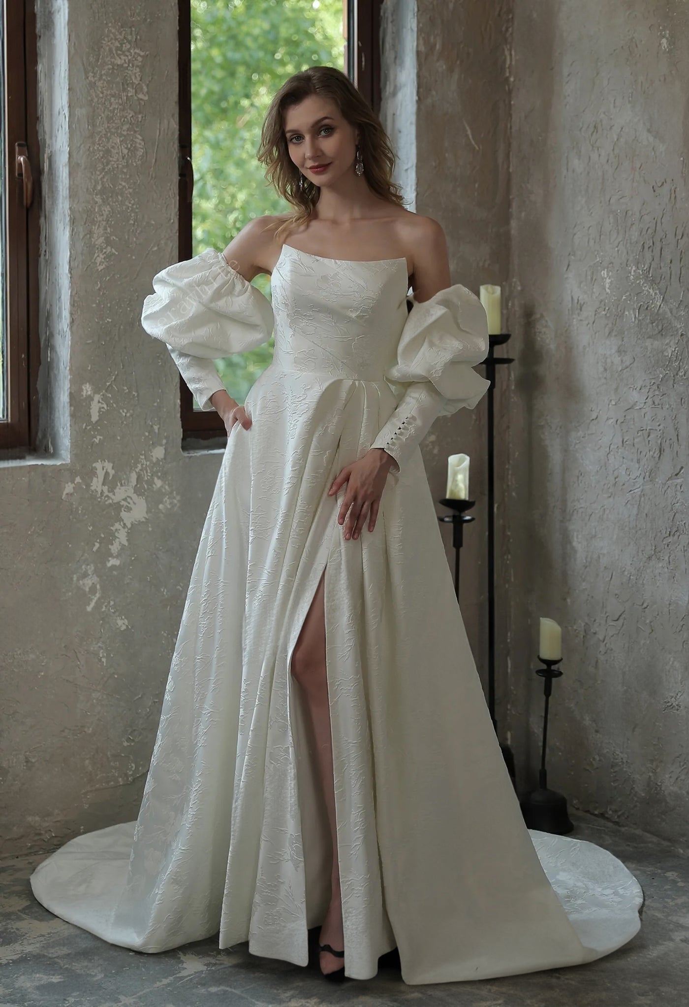 A woman in a white wedding dress is posing in front of a window at Bergamot Bridal, wearing the Modern Scoop Neckline Brocade Satin Ball gown.