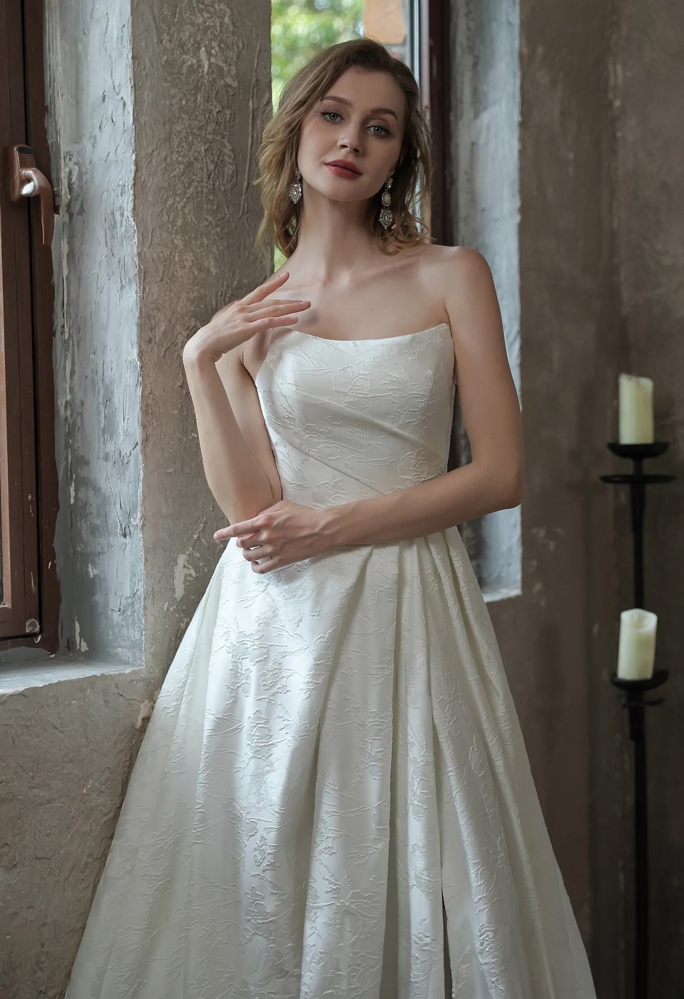 A woman in a white wedding dress, the Modern Scoop Neckline Brocade Satin Ball gown from Bergamot Bridal, leaning against a wall near a bridal shop in London.