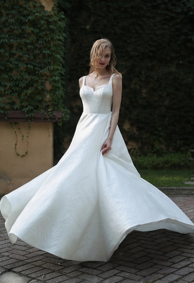 A beautiful bride in a white Minimalist Chic Modern Satin Ball Gown Wedding Dress purchased from Bergamot Bridal.
