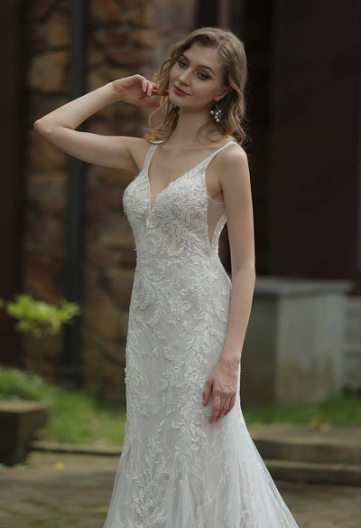 A woman in an elegant Bergamot Bridal Classic V-Neck Allover Lace Fit And Flare Wedding Dress, posing with her hand on her face.