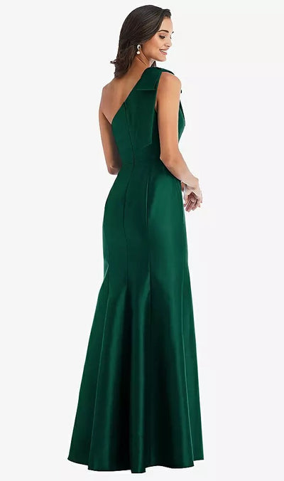 A woman in a sleeveless, floor-length green satin twill gown, posing with her back turned, showcases the elegance of the Bergamot Bridal Bow One-Shoulder Satin Trumpet Gown Bridesmaid Dress - Style D794 by Dessy.