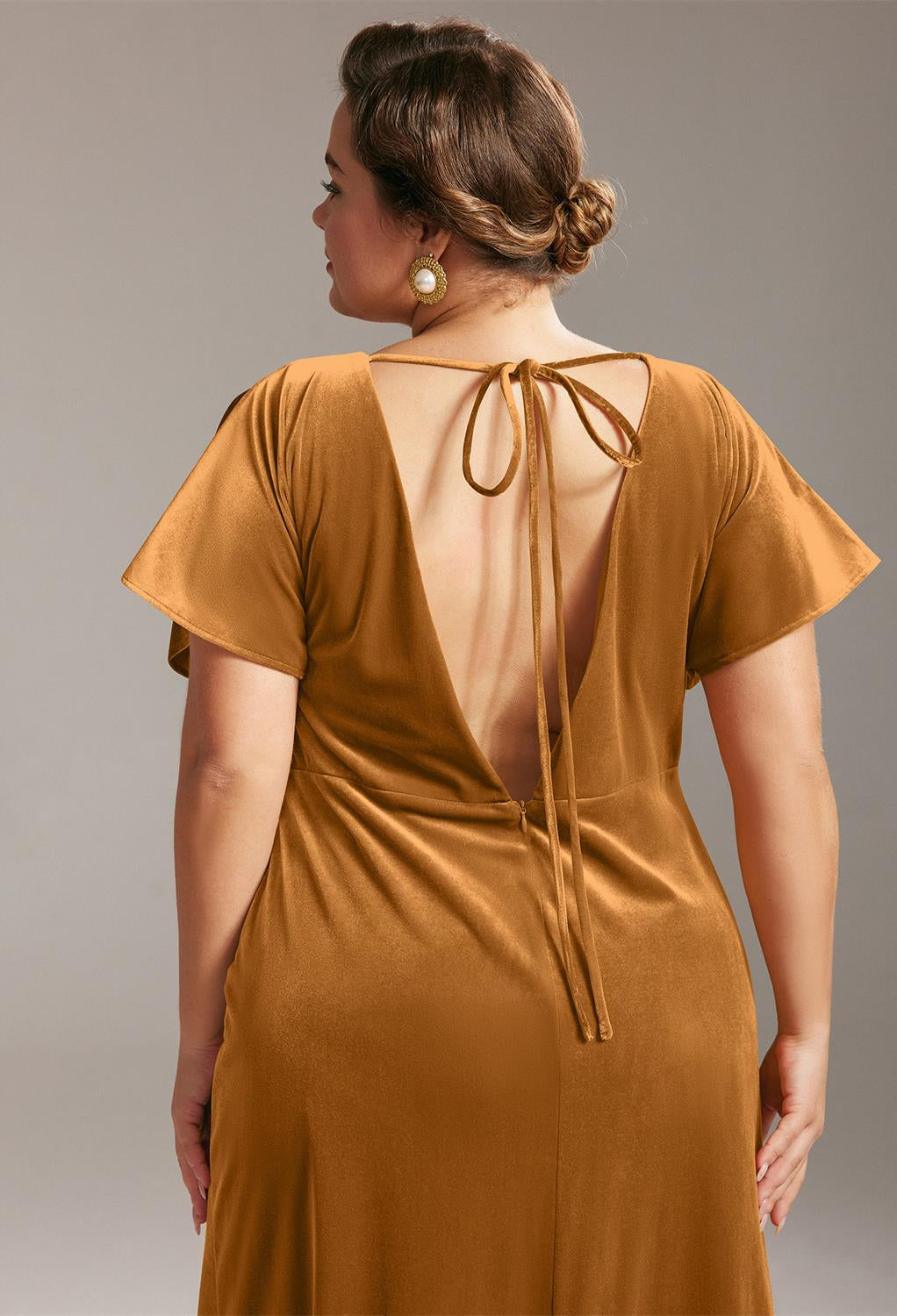 The back view of a woman wearing a Meara - Velvet Bridesmaid Dress - Off The Rack in a Bergamot Bridal shop.