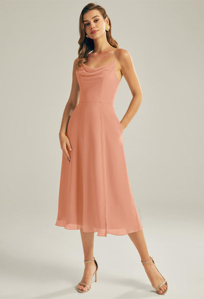 A woman in the Maribel Chiffon Bridesmaid Dress by Bergamot Bridal, paired with strappy heels, stands against a neutral background.