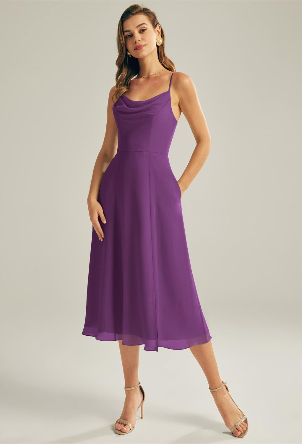 A woman wearing the Maribel chiffon bridesmaid dress from Bergamot Bridal, complete with a chic sleeveless design and deep pockets, pairs it with beige heels while exploring bridal shops in London for her upcoming event.