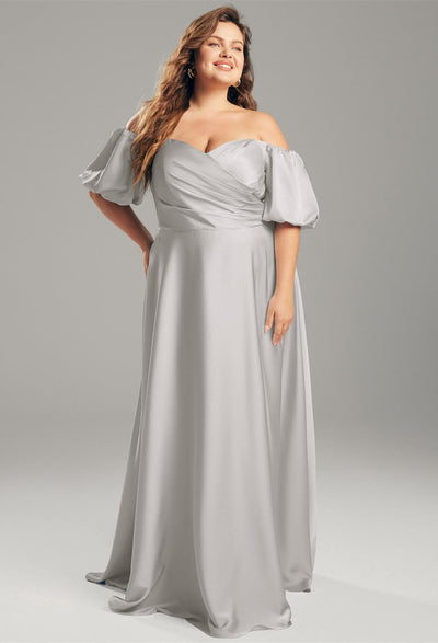 A plus size bride in a grey off the shoulder gown, the Dey - Satin Charmeuse Bridesmaid Dress - Off The Rack by Bergamot Bridal, at a bridal shop.
