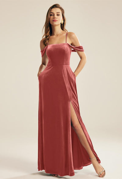 A woman in a Lowell - Velvet Bridesmaid Dress - Off The Rack from Bergamot Bridal, with a high slit, standing confidently against a light background.