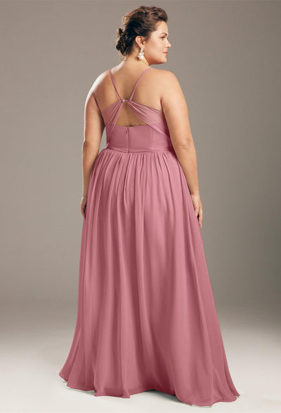 A woman in an elegant pink Wilfreda - Chiffon Bridesmaid Dress - Off The Rack looks over her shoulder, standing against a neutral background from Bergamot Bridal.