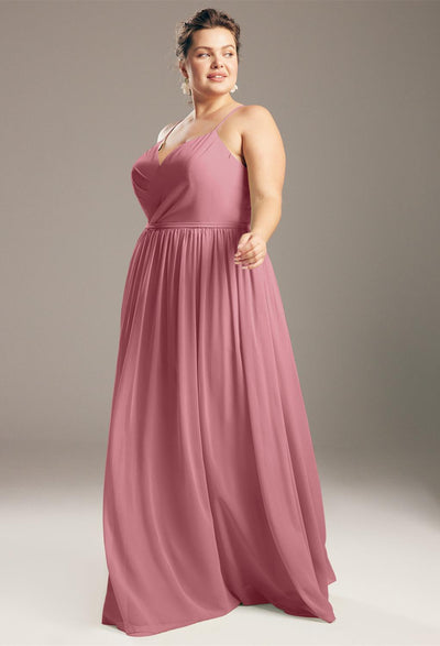 Woman in an elegant pink Wilfreda - Chiffon Bridesmaid Dress - Off The Rack standing confidently with one hand on her hip and smiling from Bergamot Bridal.