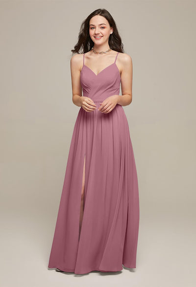 Woman wearing a mauve sleeveless Wilfreda chiffon bridesmaid gown with a V-neckline and pleated skirt, standing against a neutral background, smiling.