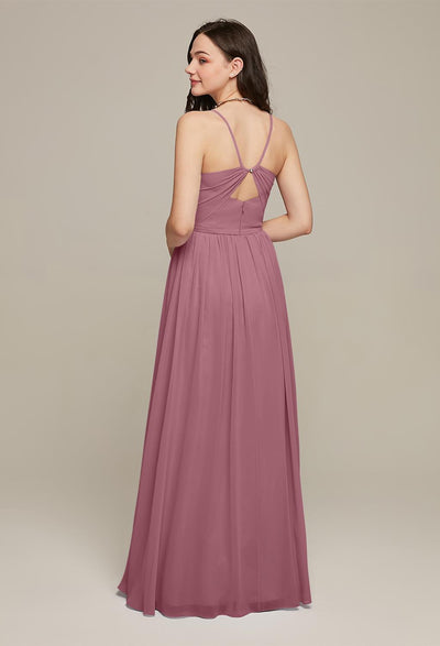 Woman wearing a mauve floor-length Wilfreda - Chiffon Bridesmaid Dress - Off The Rack from Bergamot Bridal, with a criss-cross back design, viewed from behind. She is looking to the side and standing against