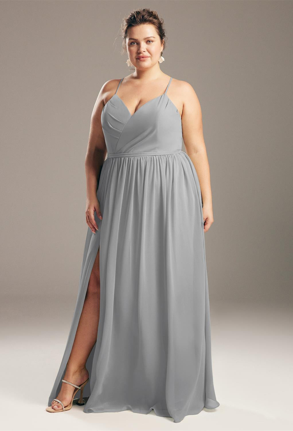 A person wearing the Wilfreda - Chiffon Bridesmaid Dress by Bergamot Bridal poses against a neutral background, reminiscent of the elegant collections from bridal shops in London, Ontario.