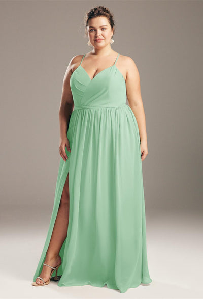 A woman in a mint green wedding gown with a halter neckline and a slit, standing confidently against a neutral background wearing the Bergamot Bridal's Wilfreda - Chiffon Bridesmaid Dress - Off The Rack.