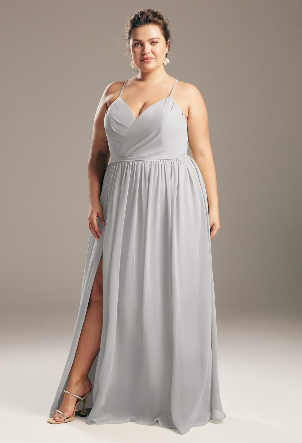 Woman in a gray Wilfreda - Chiffon Bridesmaid Dress - Off The Rack by Bergamot Bridal with a thigh-high slit, standing confidently against a neutral background.