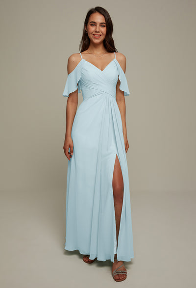 A person is wearing the Jenifer Chiffon Bridesmaid Dress by Bergamot Bridal, featuring a light blue, off-shoulder design with a slit, standing against a plain background reminiscent of bridesmaid dresses found in bridal shops in London, Ontario.