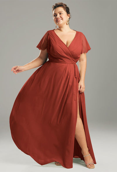 Wearing the Ellison Chiffon Bridesmaid Dress by Bergamot Bridal, a person poses gracefully against a gray background, exuding an elegance similar to the refined bridesmaid dresses available in bridal shops across London, Ontario.