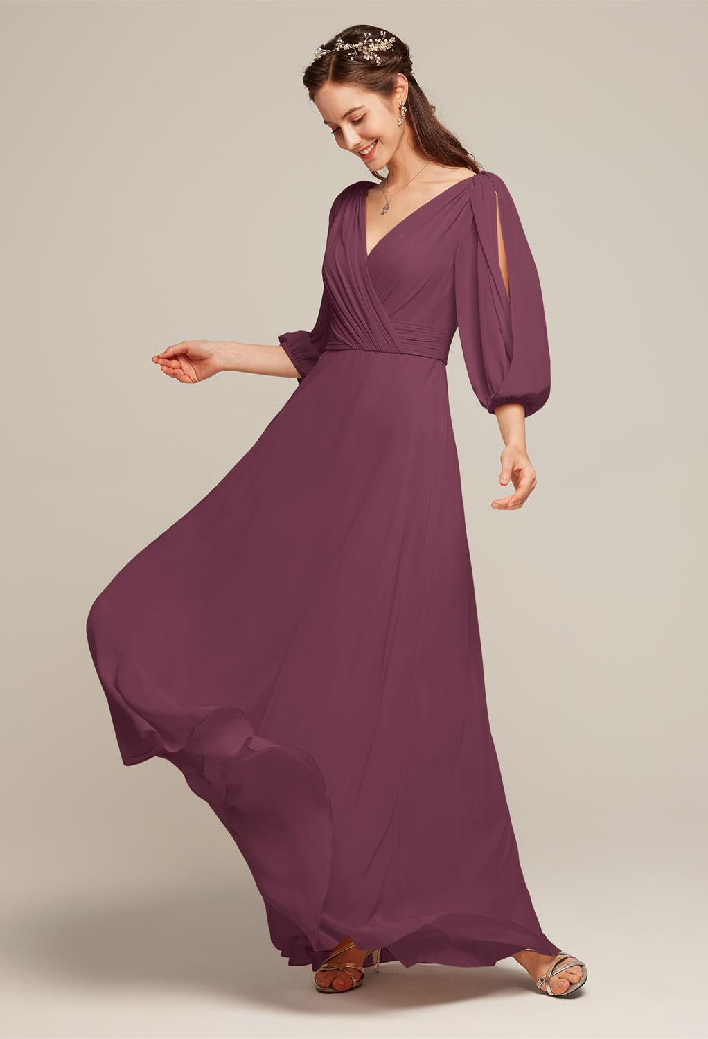 A woman in a long, chiffon off-the-rack bridesmaid dress from Bergamot Bridal, complete with puff sleeves and sandals, twirls with a smile against a neutral background as she envisions herself among the elegant Polly collection at a bridal shop in London.