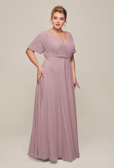 A woman exudes grace and sophistication as she poses in a flowing, mauve Ginny chiffon bridesmaid dress from Bergamot Bridal against a neutral backdrop, reflecting the style found in bridal shops in London, Ontario.