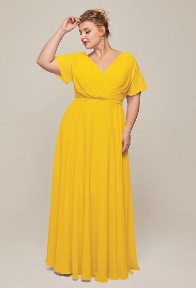 A woman in a yellow v-neck gown poses elegantly, hand resting on her head against a neutral backdrop. For affordable wedding dress options or stunning bridesmaid dresses, discover styles as captivating as this Ginny Chiffon Bridesmaid Dress from Bergamot Bridal at the bridal shop in London, Ontario.