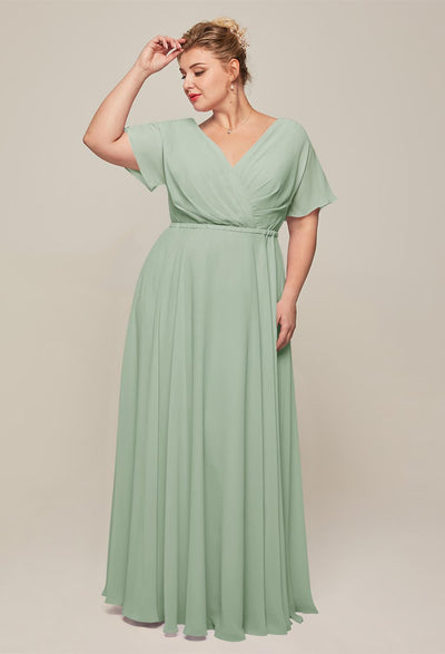 A plus size bridesmaid wearing a Ginny - Chiffon Bridesmaid Dress - Off The Rack in sage green at a Bergamot Bridal shop in London.