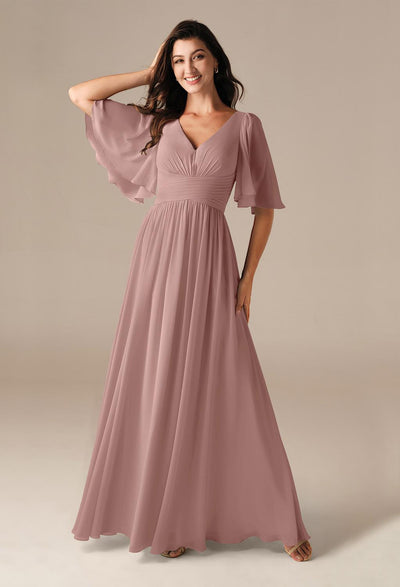 A person models a long, flowing chiffon dress with flutter sleeves in a mauve shade, reminiscent of the elegant Kenney bridesmaid dresses by Bergamot Bridal that are found in bridal shops throughout London, Ontario.