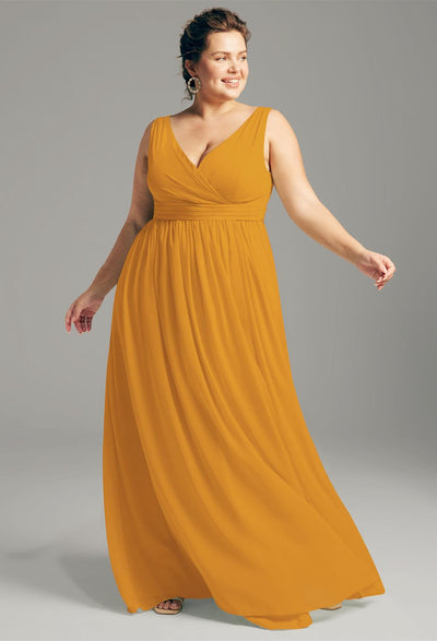 A person wearing the Hilaria, a sleeveless, floor-length chiffon bridesmaid dress from Bergamot Bridal's Off the Rack collection, poses gracefully against a neutral background, reminiscent of the elegant styles found in bridal shops in London, Ontario.