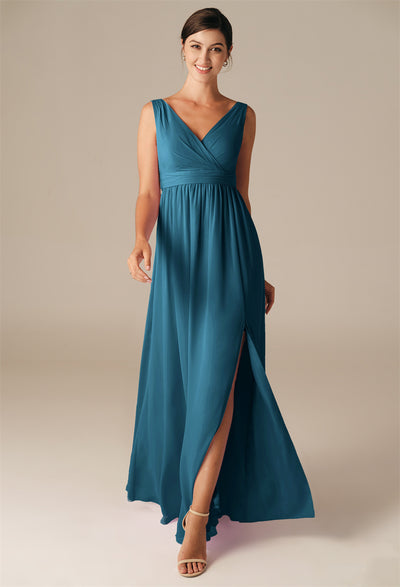 A woman wearing the Hilaria chiffon bridesmaid dress by Bergamot Bridal, featuring a teal hue, sleeveless design, V-neckline, and thigh-high slit, stands gracefully against a neutral background, reminiscent of the elegant selections found at bridal shops in London, Ontario.