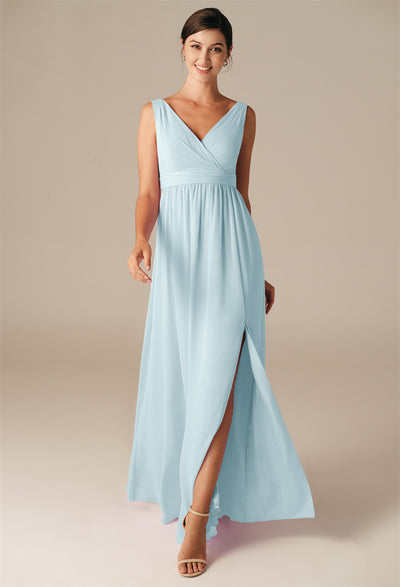 A woman wearing the Hilaria chiffon bridesmaid dress by Bergamot Bridal, featuring a sleeveless design in light blue with a deep V-neck and a front slit, stands against a neutral background, exemplifying the elegance of off-the-rack bridal shop offerings in London, Ontario.