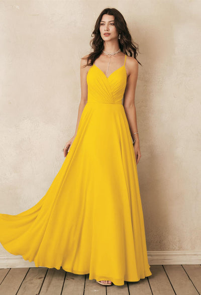 A woman stands against a textured wall wearing the Melody - Chiffon Bridesmaid Dress from Bergamot Bridal, evoking the elegance of off-the-rack bridesmaid dresses found in bridal shops around London, Ontario.