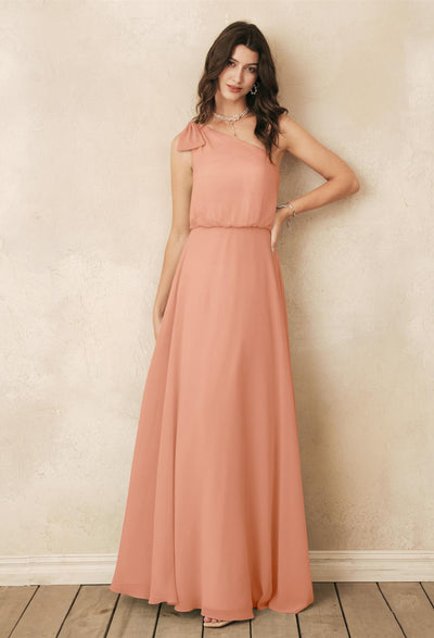 A woman gracefully poses against a textured wall in a long, sleeveless chiffon dress from Bergamot Bridal's London, Ontario store. Her hand rests confidently on her hip, embodying the poise of someone who has discovered their ideal bridesmaid attire with the Robina - Chiffon Bridesmaid Dress - Off The Rack.