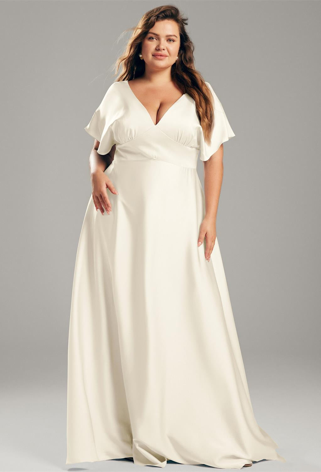 A plus size bride in a white gown, the Nora - Satin Charmeuse Bridesmaid Dress - Off The Rack from Bergamot Bridal, with a v-neck and v-back.