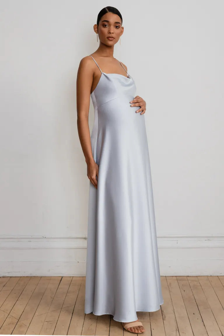 A woman in a simple, elegant white Addison - Bridesmaid Dress by Jenny Yoo with an empire waist stands against a plain background.