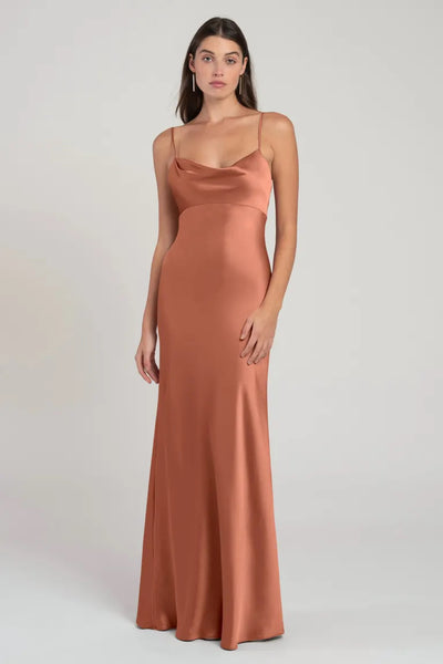 Woman posing in an elegant, satin, terracotta Addison - Bridesmaid Dress by Jenny Yoo with an empire waist and thin straps from Bergamot Bridal.