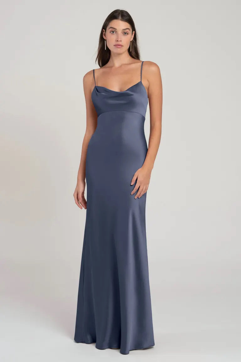 Woman modeling a sleek, slate blue Addison bridesmaid dress by Jenny Yoo with spaghetti straps and an empire waist from Bergamot Bridal.