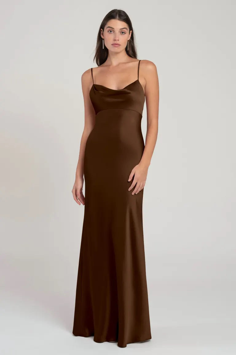 Woman in a long brown satin slip dress with an empire waist posing against a neutral background, wearing the Addison Bridesmaid Dress by Jenny Yoo from Bergamot Bridal.