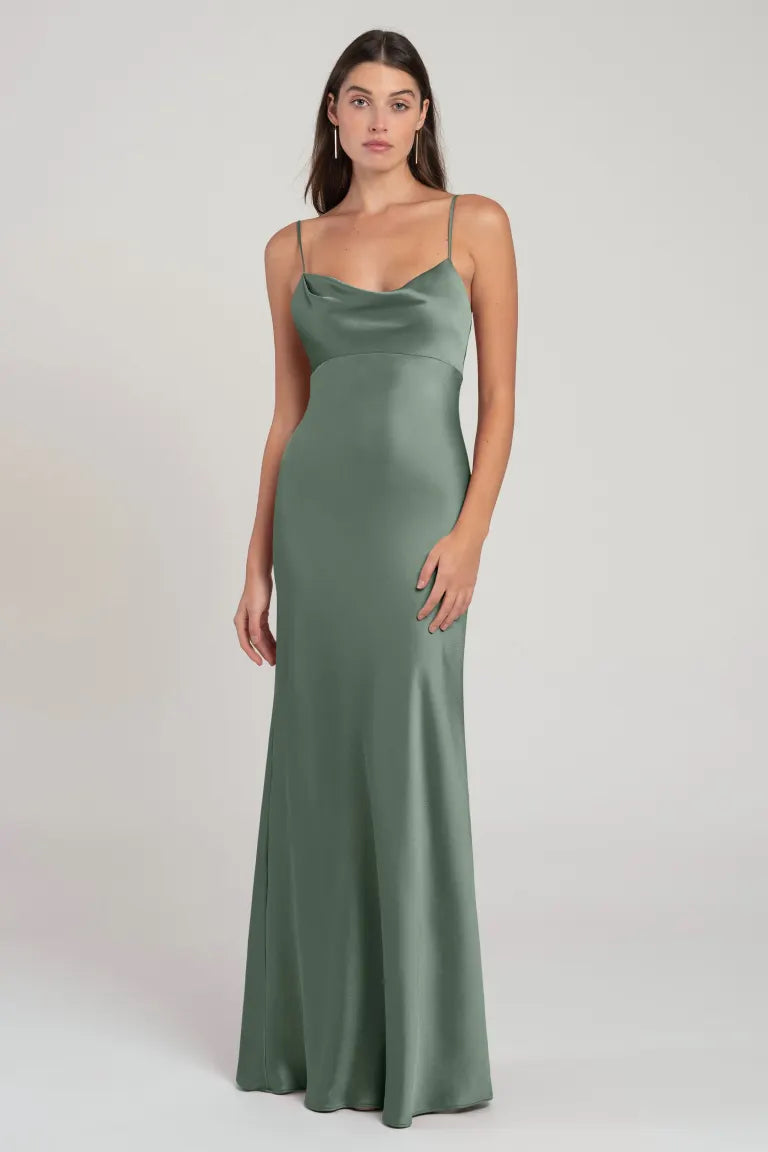 Woman posing in a long, sage green, Addison - Bridesmaid Dress by Jenny Yoo satin cowl neck dress with an empire waist from Bergamot Bridal.