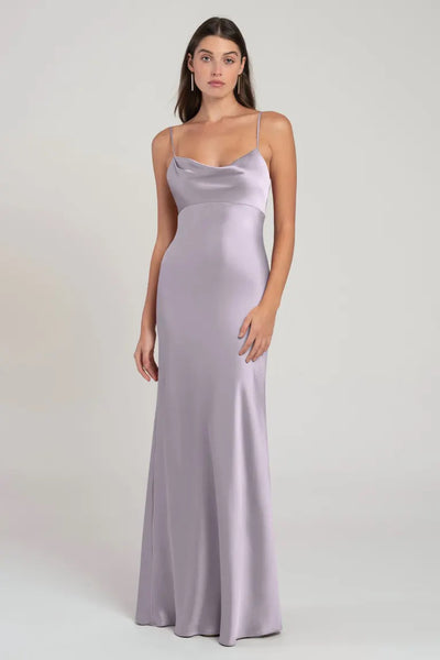 Woman in a long, satin, lavender bridesmaid dress with an empire waist standing against a neutral background. 
Product Name: Addison - Bridesmaid Dress by Jenny Yoo
Brand Name: Bergamot Bridal