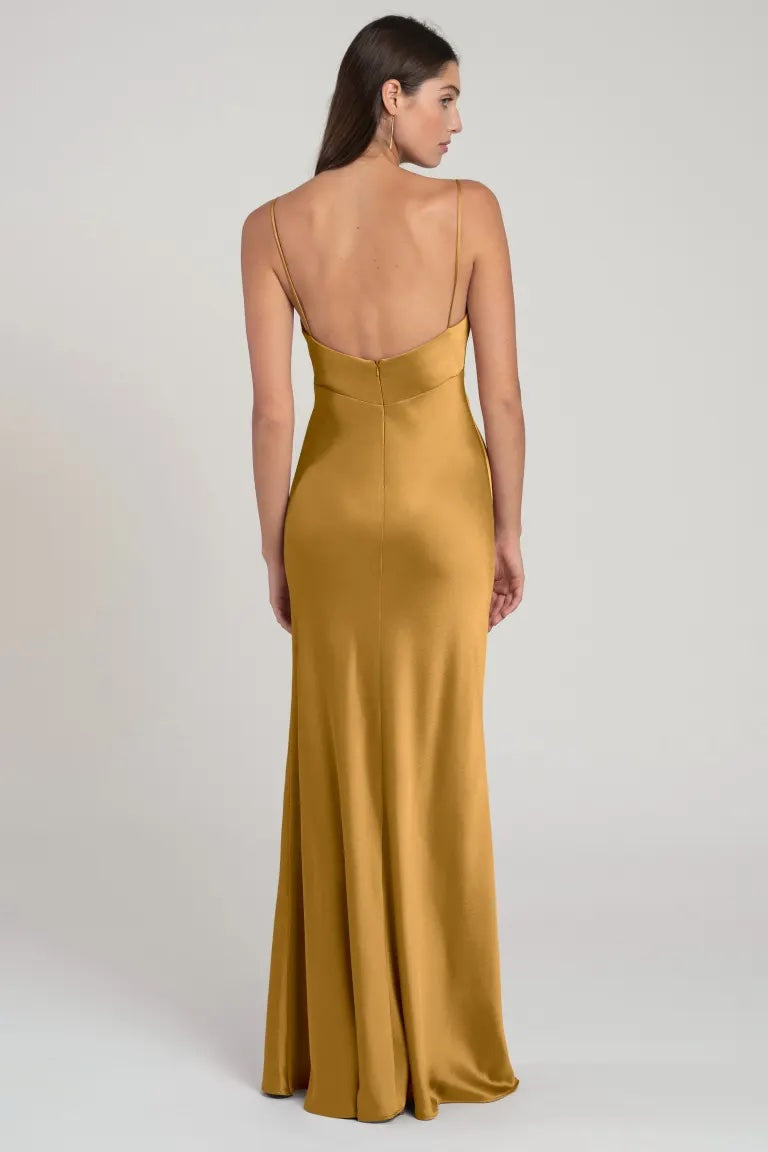Woman in an elegant gold satin slip dress with a low back, standing against a neutral background - Addison Bridesmaid Dress by Jenny Yoo at Bergamot Bridal.