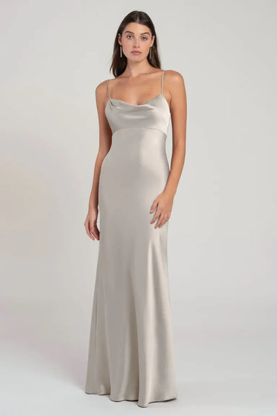 A woman in a sleek, empire waist Addison - Bridesmaid Dress by Jenny Yoo stands against a neutral background.