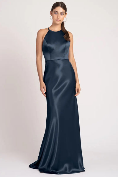 Woman posing in an elegant navy blue Alessia - Bridesmaid Dress by Jenny Yoo evening gown with a high neckline from Bergamot Bridal.