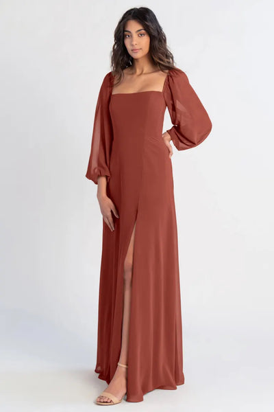 Woman posing in an elegant brown Althea - Bridesmaid Dress by Jenny Yoo from Bergamot Bridal with a thigh-high slit, puff sleeves, and an A-line skirt.