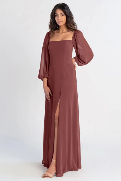 A woman in an elegant brown chiffon Althea bridesmaid dress by Jenny Yoo with a thigh-high slit posing for a photo from Bergamot Bridal.