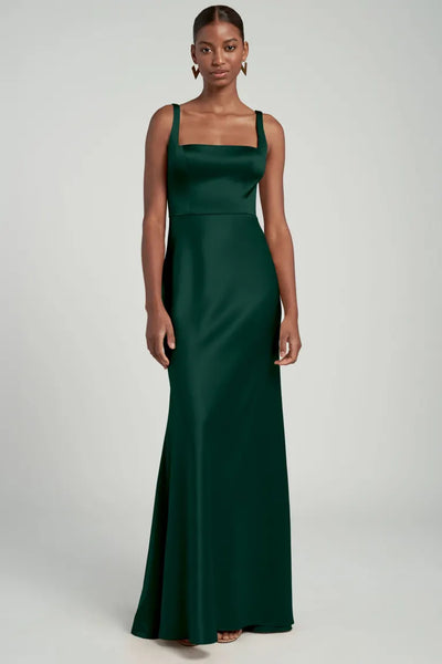 Woman in an elegant green evening gown with a square neckline, wearing the Ariana - Bridesmaid Dress by Jenny Yoo from Bergamot Bridal.