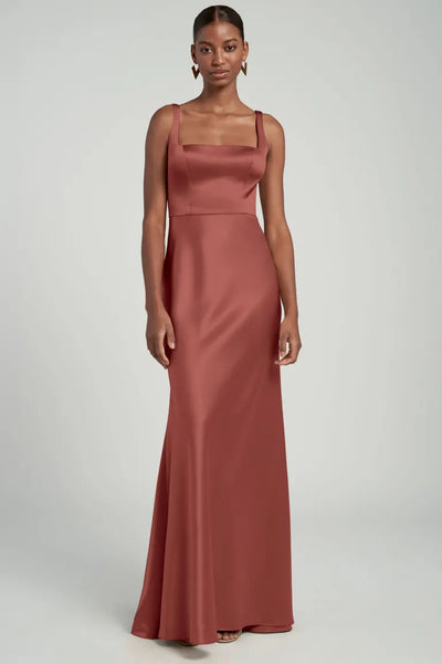 Woman posing in a sleeveless, square-neckline, rose-colored satin back crepe Ariana bridesmaid dress by Jenny Yoo from Bergamot Bridal.