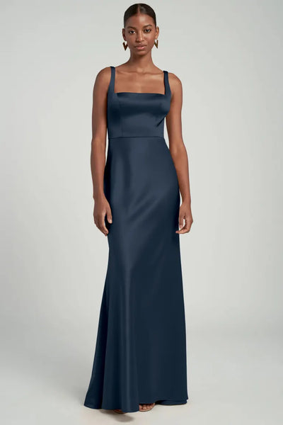 Ariana posing in a formal blue satin back crepe bridesmaid dress with square neckline and spaghetti straps by Bergamot Bridal, the Bridesmaid Dress by Jenny Yoo.