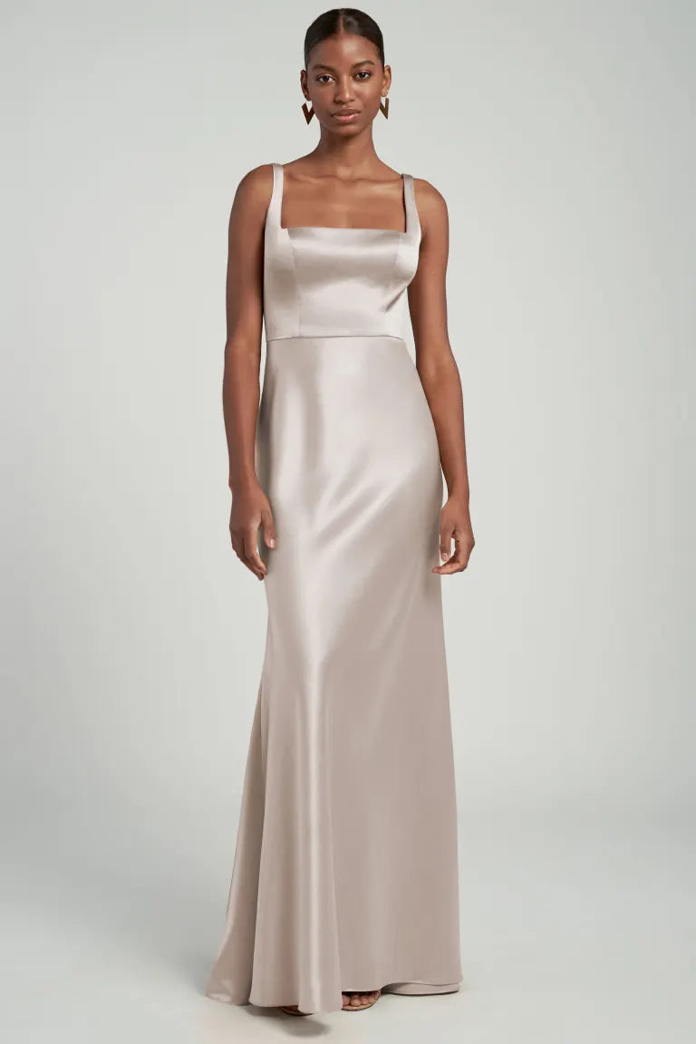 A woman modeling a sleeveless, floor-length Ariana bridesmaid dress by Jenny Yoo with a square neck from Bergamot Bridal.