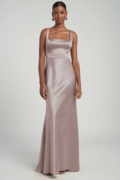 Woman posing in an elegant mauve Ariana bridesmaid dress by Jenny Yoo with wide-set straps from Bergamot Bridal.