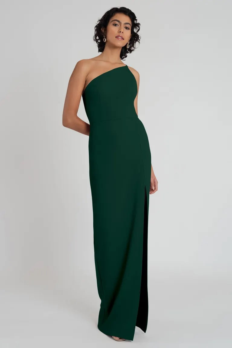 Woman in an elegant green knit crepe Aubrey bridesmaid dress by Jenny Yoo with a one-shoulder neckline from Bergamot Bridal.