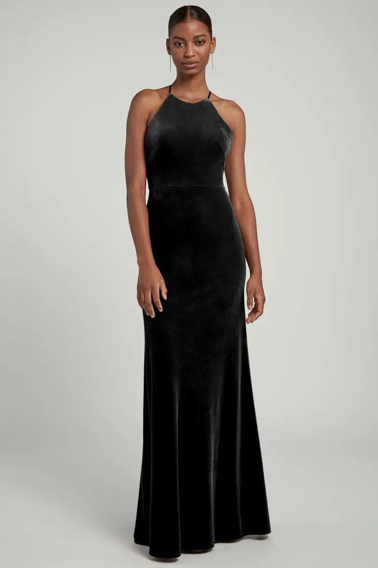 Woman posing in an elegant black Bailey velvet dress with a halter neckline by Bergamot Bridal.