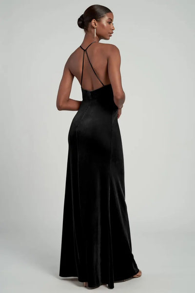 Woman in an elegant Jenny Yoo Bailey velvet bridesmaid dress with a halter neckline and a low-cut back standing against a neutral backdrop from Bergamot Bridal.
