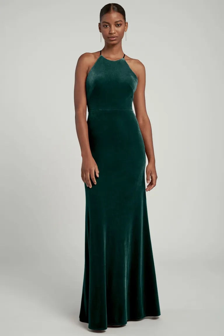 A woman standing in an elegant green Bailey bridesmaid dress by Jenny Yoo with a halter neckline from Bergamot Bridal.